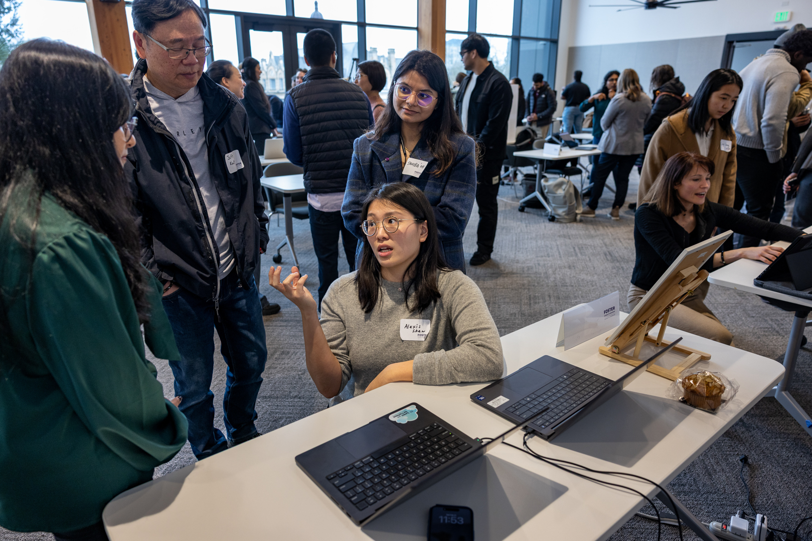 Student explaining a project at her table while attendees gather nearby.