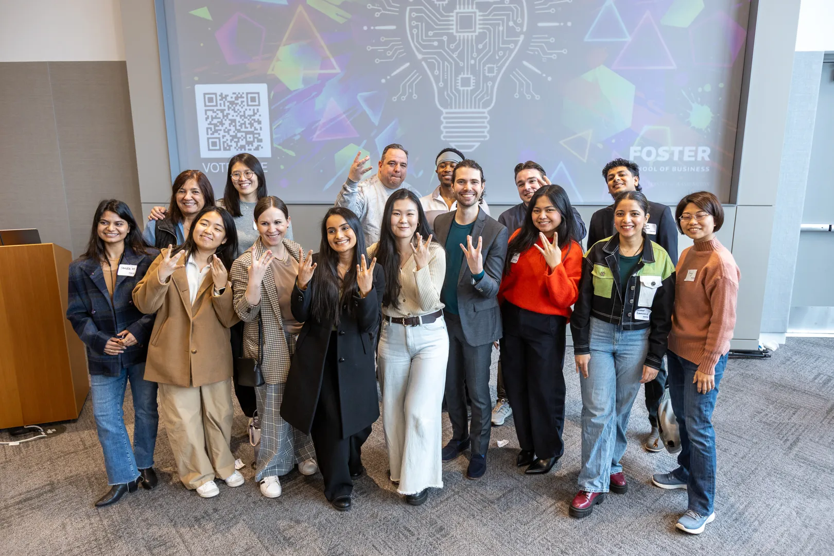 Students and faculty posing together in front of the fair screen after the event.