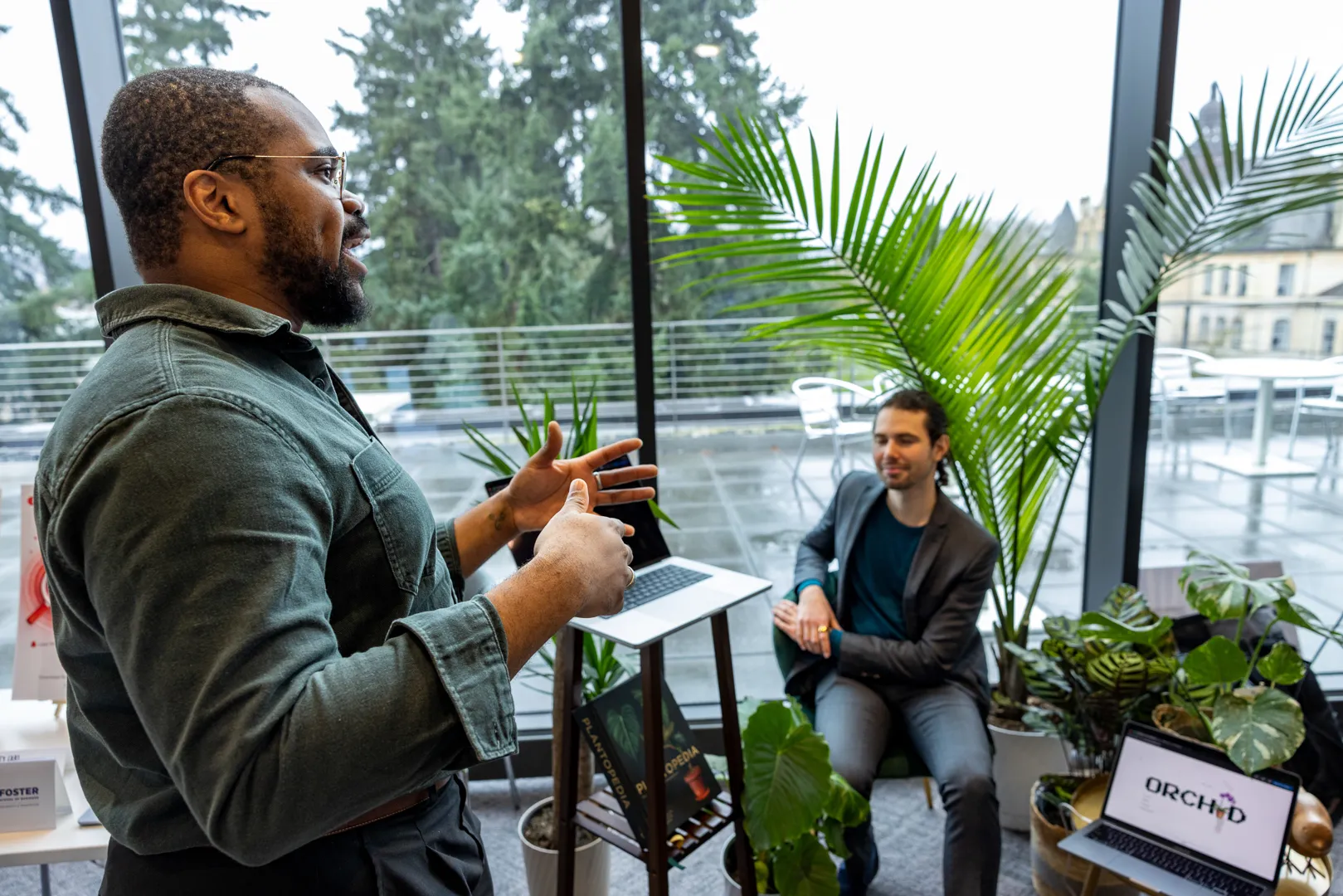 Masud Lewis presenting Orchid near a display of plants and demo materials.