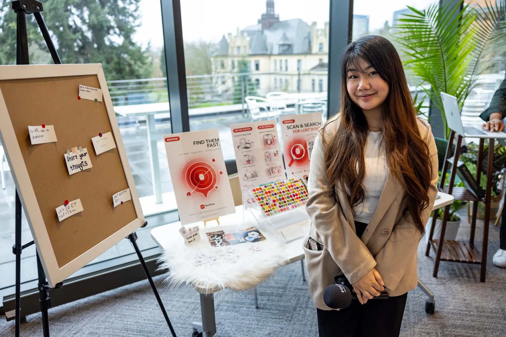 Student standing beside Redpaw project materials and presentation board at the fair.